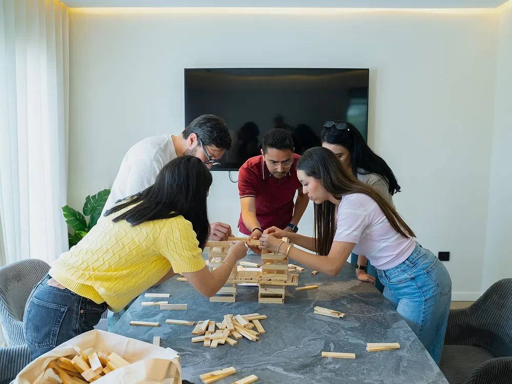 Une équipe penchée sur une table construit une tour en planchettes de bois.