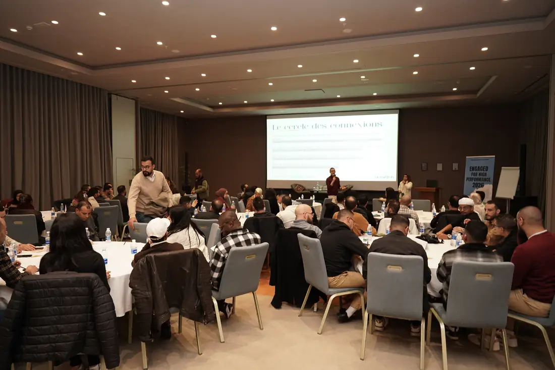 La salle en tables rondes, l'écran affichant les questions du cercle d'ouverture en français et en anglais.