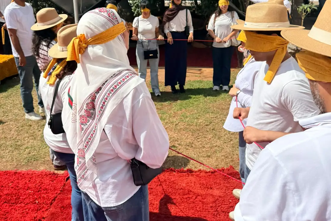 Un sous-groupe, les yeux bandés d'un foulard jaune, manipule une corde en extérieur.